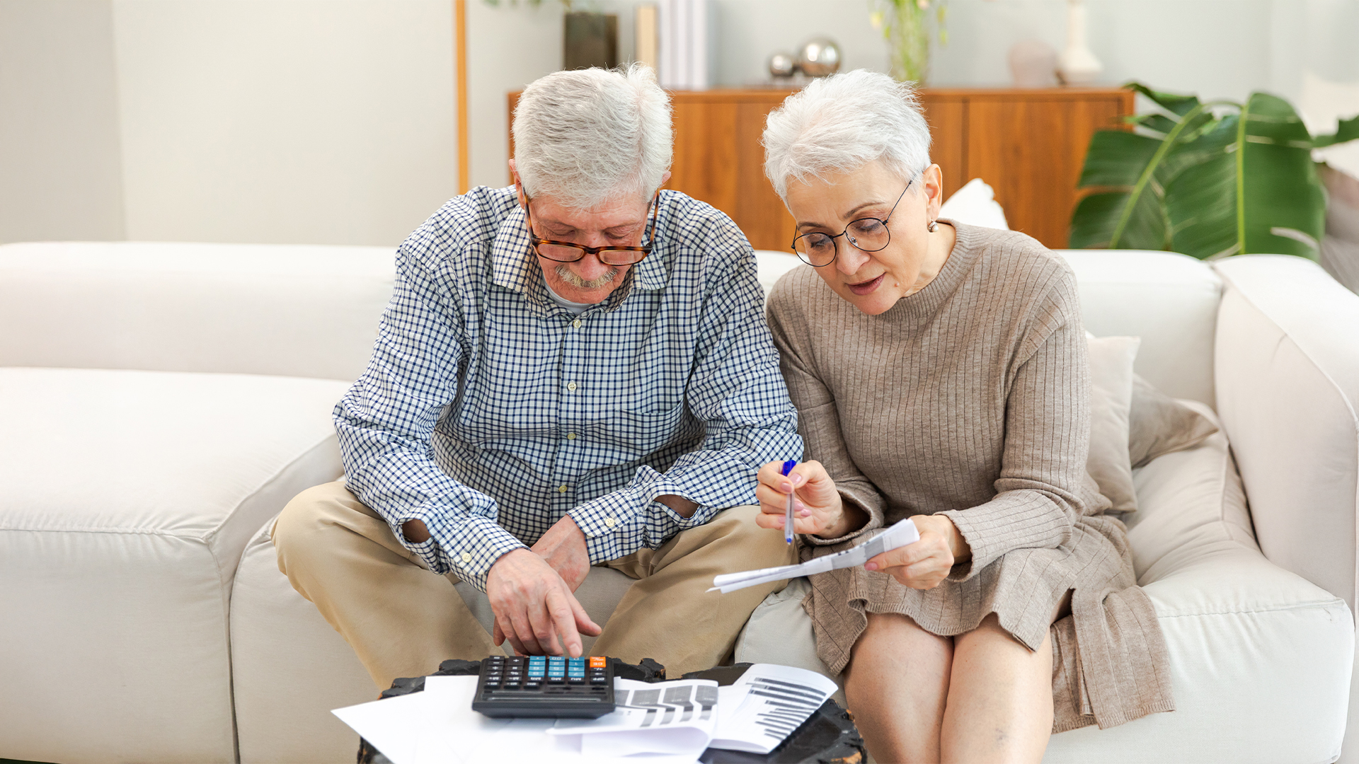 Middle aged senior couple sit with laptop and paper document